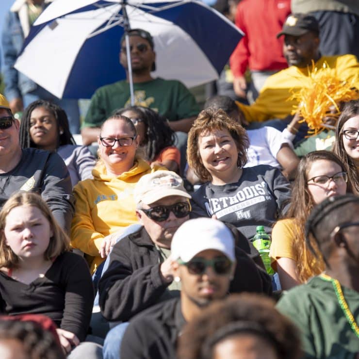 Alumni sit together to watch a Methodist University Homecoming game
