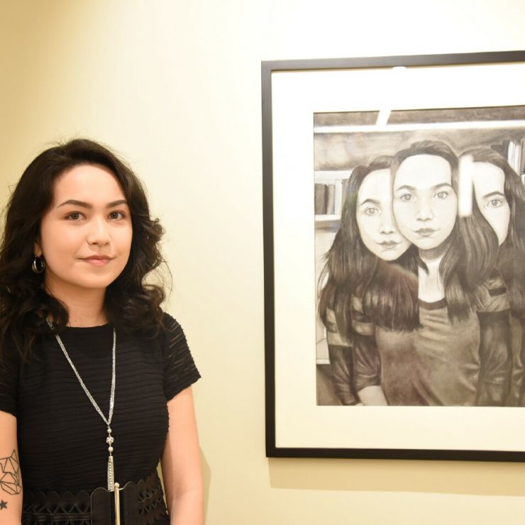 A studentposes with her artwork in the Union-Zukowski Lobby & Gallery