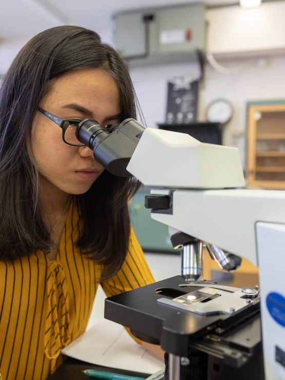 Biology student looking through microscope at Methodist University