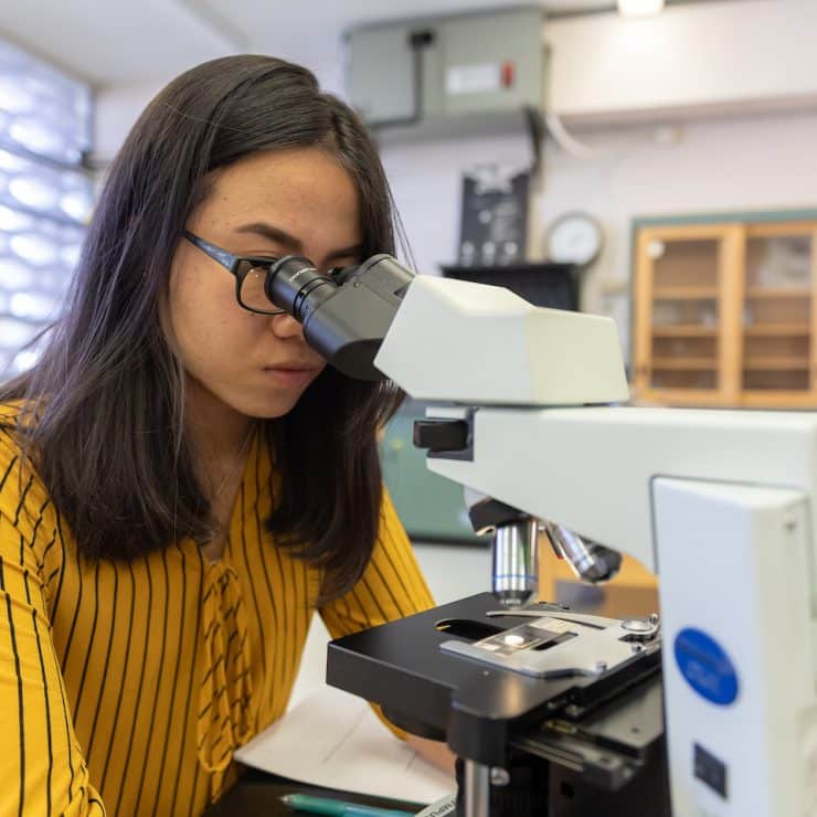 Biology student looking through microscope at Methodist University
