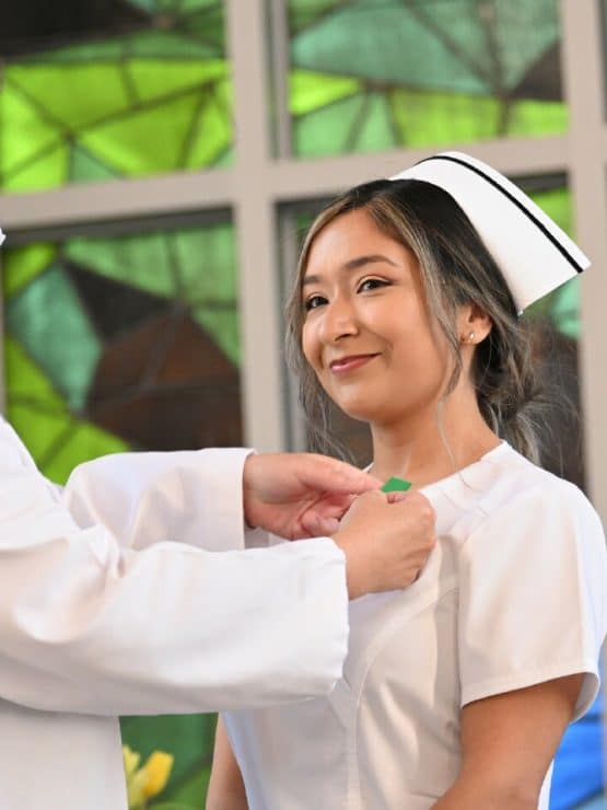 Dr. Matthews pins a student nurse