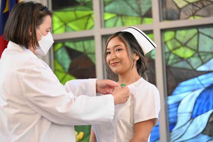 Dr. Matthews pins a student nurse