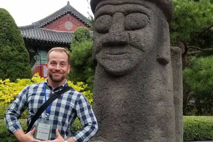 Dr. J. R. Hustwit poses with a Dol Hareubang, a stone guardian, at the Yeoju Temple Headquarters of Daesoon Jinrihoe, a Korean new religious movement.