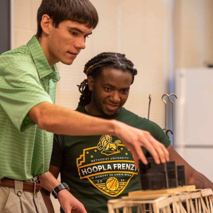 A pair of Engineering students test the bridge they made at Methodist University