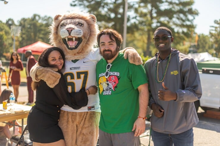 Three Methodist University students pose for a photo with King, the University’s mascot, during the annual Homecoming Tailgate on campus.
