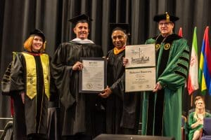 John “Mac” Healy (second from left), the MU Board of Trustees’ immediate past chair, is presented with an honorary Doctorate of Humanities by Provost Dr. Suzanne Blum Malley (left), MU Board of Trustees Chair Dr. Rakesh Gupta (second from right), and President Wearden (right).