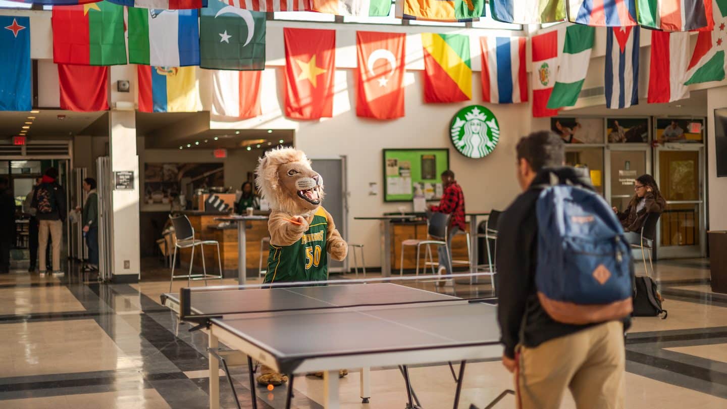 Methodist University mascot King play ping pong with a student
