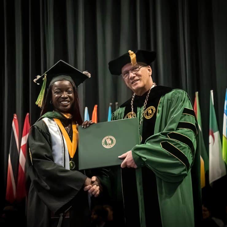 Methodist University President Stanley T. Wearden stands with a graduate during a Winter Commencement at Crown Coliseum in 2022.