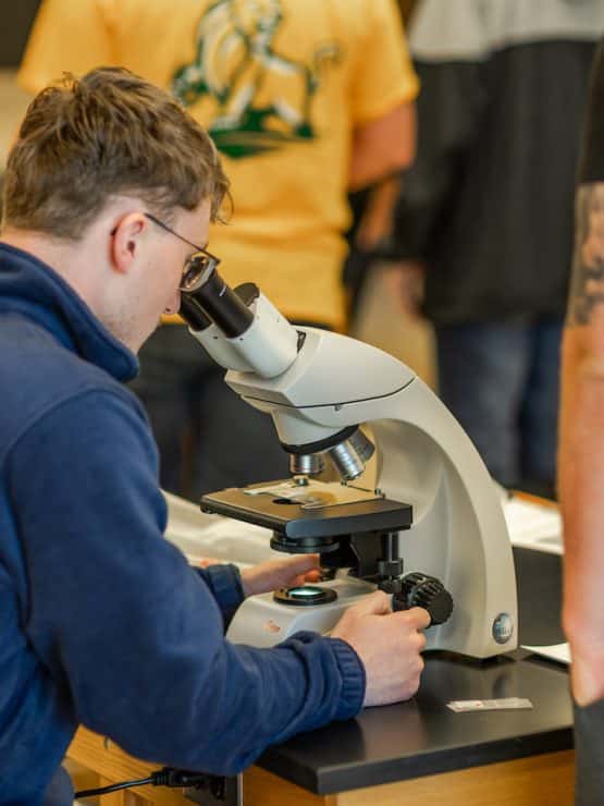 Methodist University Biology student looks into a microscope during class.
