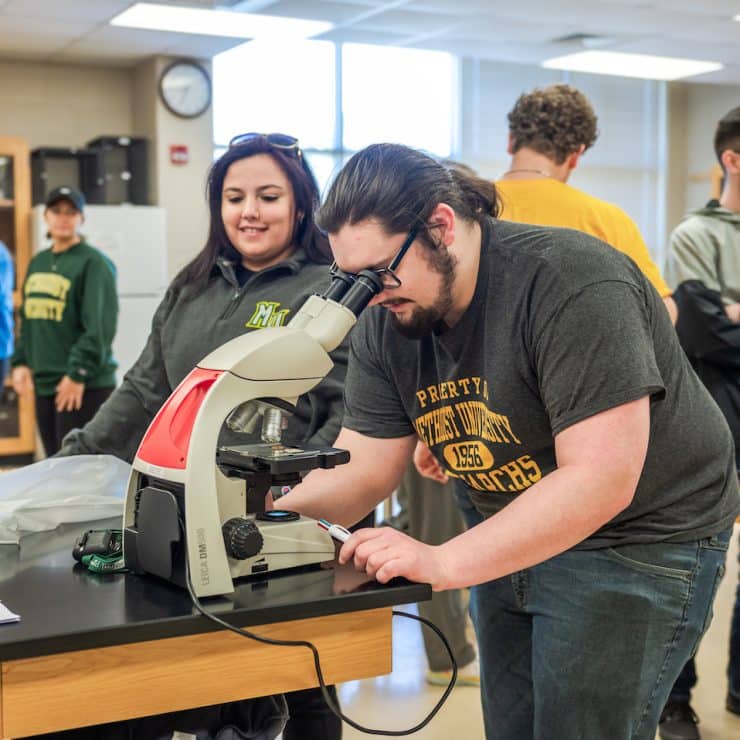 Methodist University Biology student looks into a microscope.