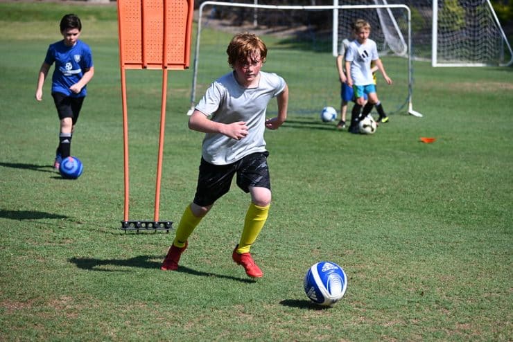 A Boys Soccer Camp participant dribbles the ball