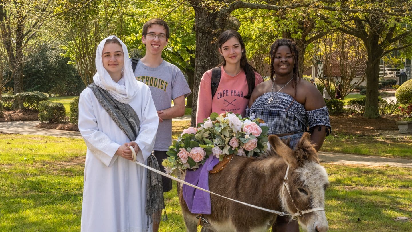 Students pose with a donkey on Palm Sunday
