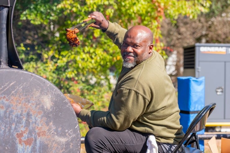 A man prepares pork barbecue on campus