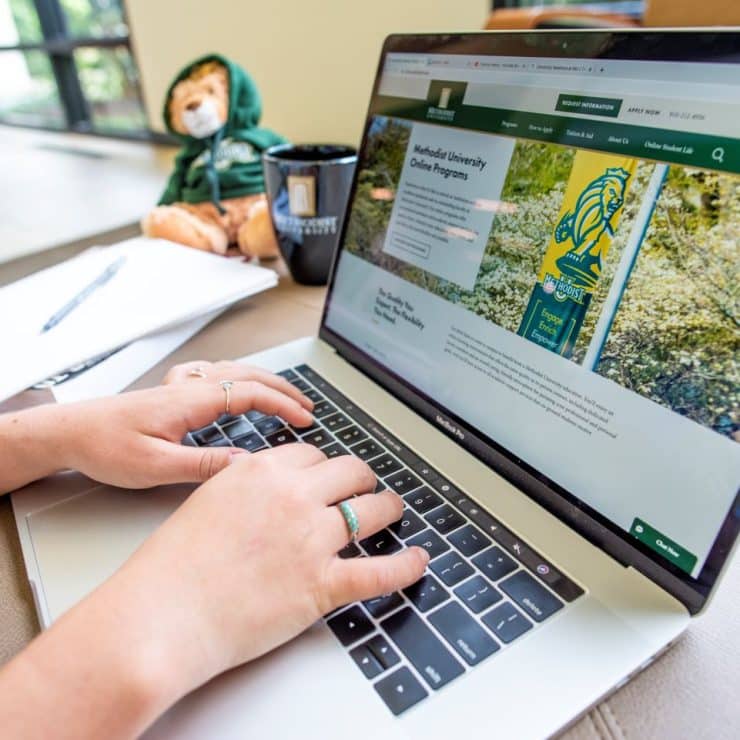 A student browses the Methodist University Online Web site on a laptop