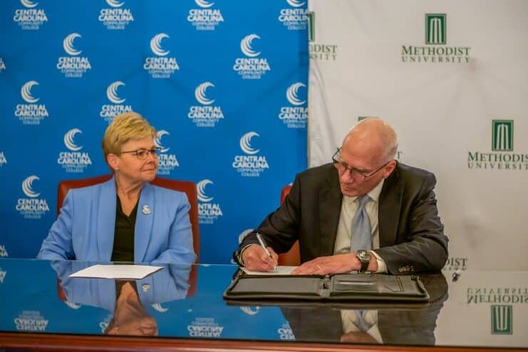 Central Carolina Community College President Dr. Lisa M. Chapman (left) and Methodist University President Dr. Stanley T. Wearden (right) sign an agreement that will allow CCCC students an assured-entry pathway to Methodist available upon graduation.