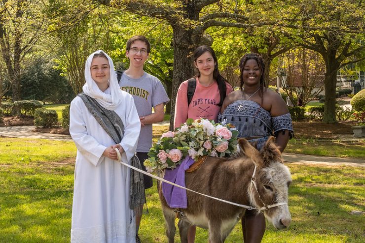 Student pose with a donkey during a Holy Week service