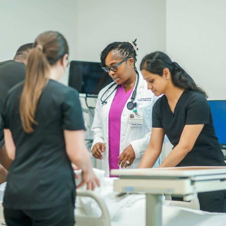 A professor and medical students work with a manakin