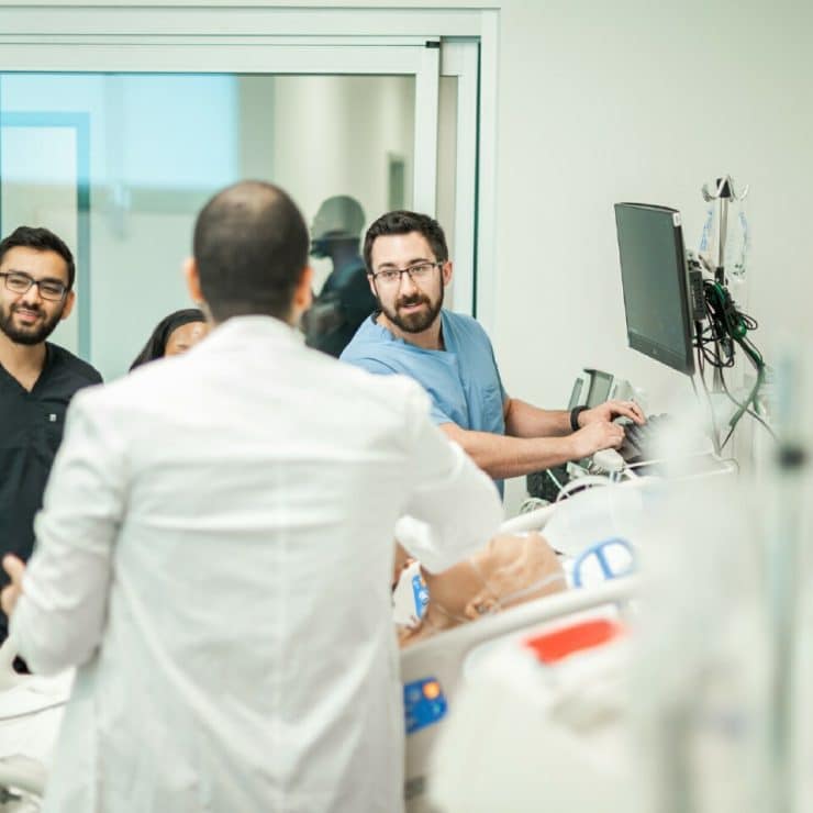 A professor and medical students work with a manakin